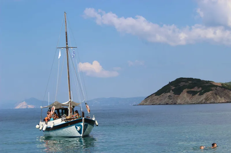 Artemida at anchor in clear water off an islet