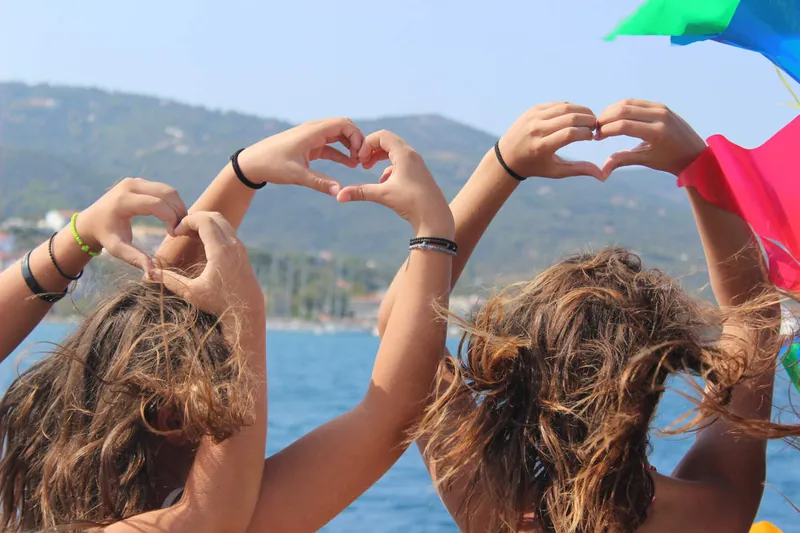 Friends making hearts with their hands at sea